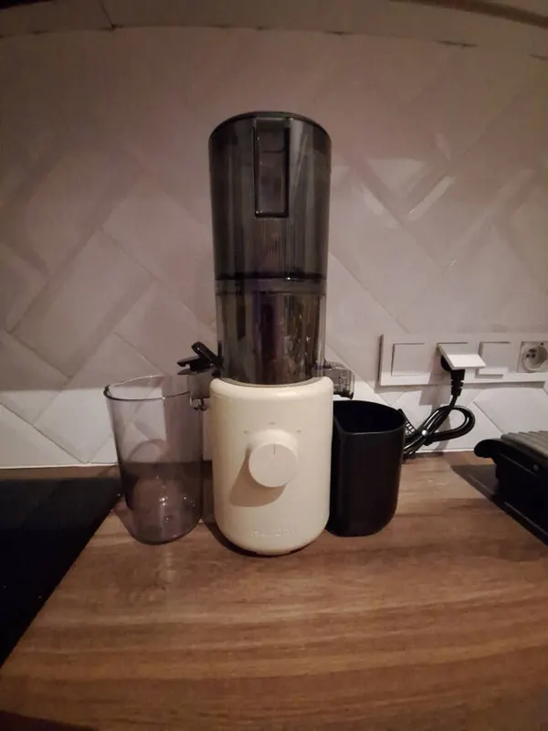 Kremowa wyciskarka Hurom H310A na drewnianym blacie