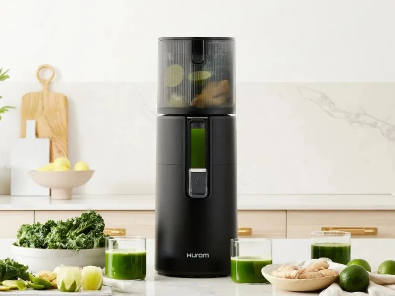 Wyciskarka Hurom H400 w jasnej kuchni, obok zielone soki i warzywa